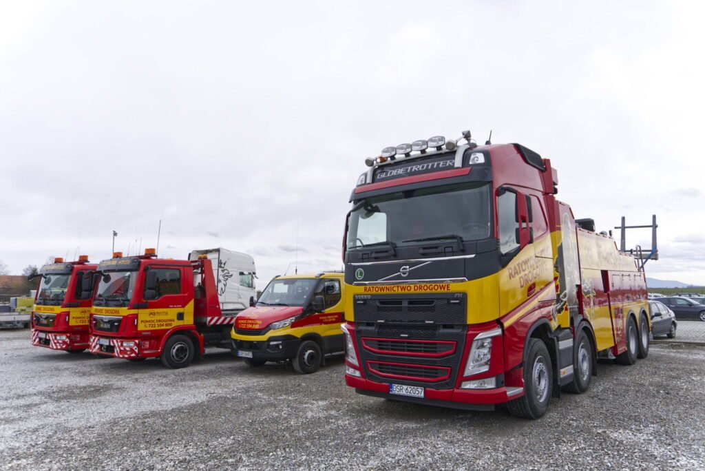 Holowanie ciężarówek Świdnica – nowoczesny holownik i lawety zaparkowane na placu firmy świadczącej pomoc drogową.